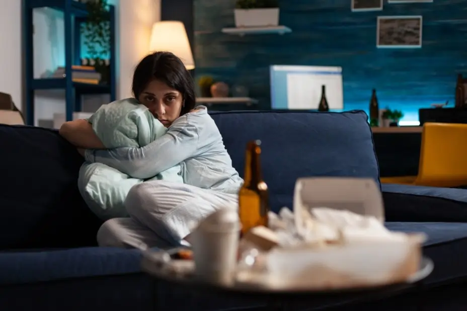 Woman hugging a pillow alone on couch, reflecting the emotional toll of anxiety and depression.