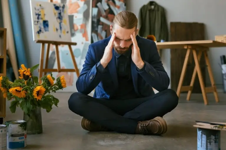 Man sitting on the floor, holding his head in distress, symbolizing anxiety. Discover the connection between folate deficiency and anxiety, its symptoms, and tips to boost folate levels for better mental health.