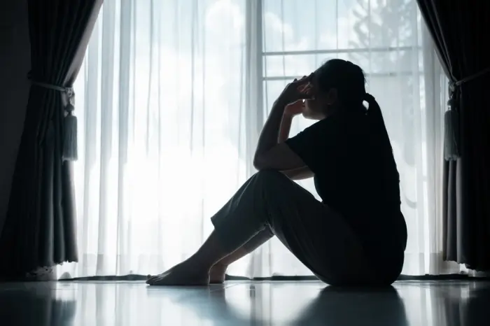 Silhouette of a lonely woman by a window, showing how isolation depression leads to projecting feelings onto others.