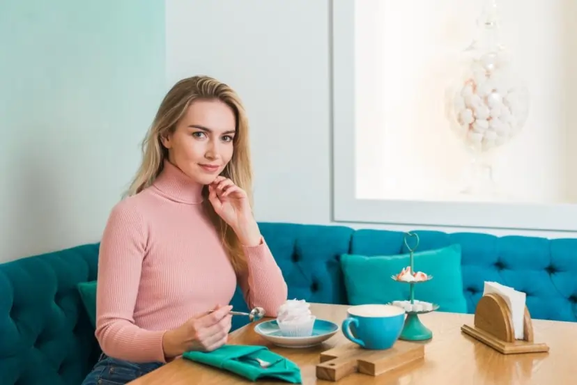 A smiling woman enjoys a treat at a cafe, demonstrating what makes self-care crucial for mental well-being.