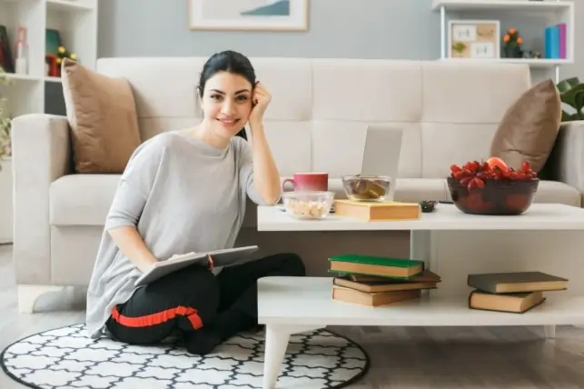 Woman practicing self-care at home with a laptop, books, and healthy snacks, focusing on mental well-being and relaxation as part of self-help strategies for depression.
