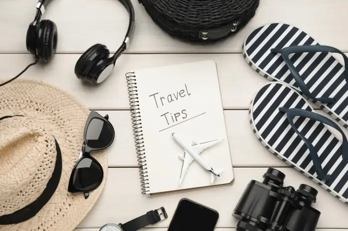 Travel essentials—notebook, headphones, sunglasses, and flip-flops—laid out flat, capturing the travel fever spirit with handy travel tips.