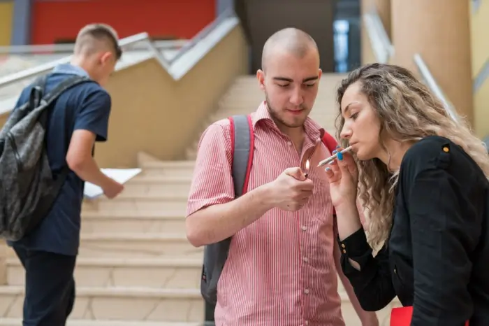 Students engaging in smoking on campus, highlighting early warning signs of addiction and peer pressure among young adults.