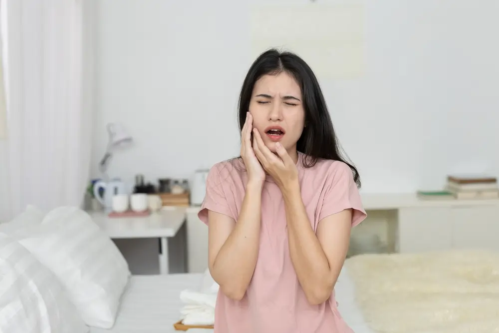 Woman holding her jaw in pain showing common cavity symptoms like toothache and dental sensitivity.
