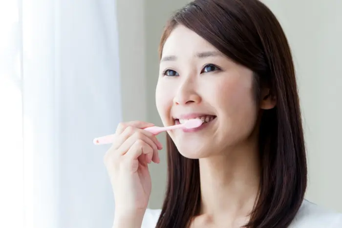 woman brushing teeth with toothbrush for dental hygiene to prevent tooth decay and cavities