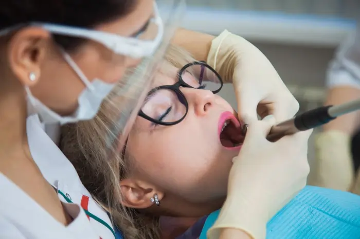 A dentist performing a molar cavity filling on a patient using professional dental tools, illustrating the restorative treatment for tooth decay.